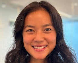 Woman with long dark hair wearing a brown sweater indoors
