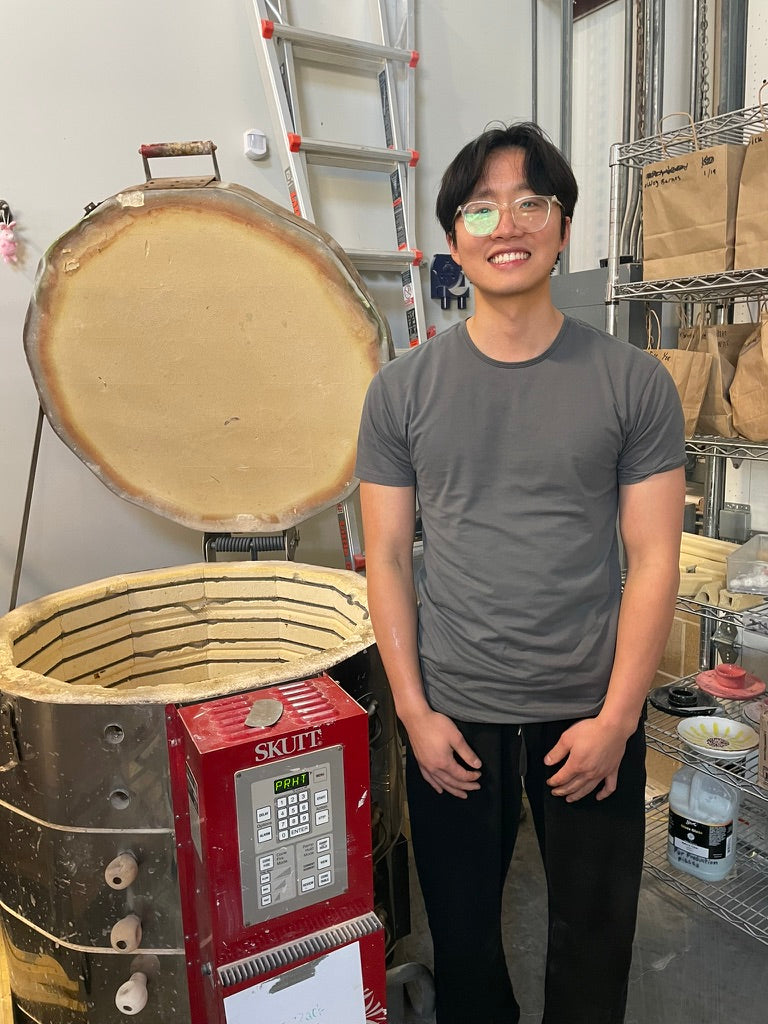 Person standing next to a large industrial oven with a SKUTT brand control panel in a workshop setting.