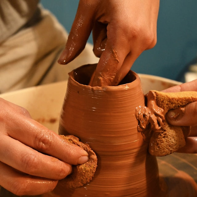 Person shaping a clay pot with their hands